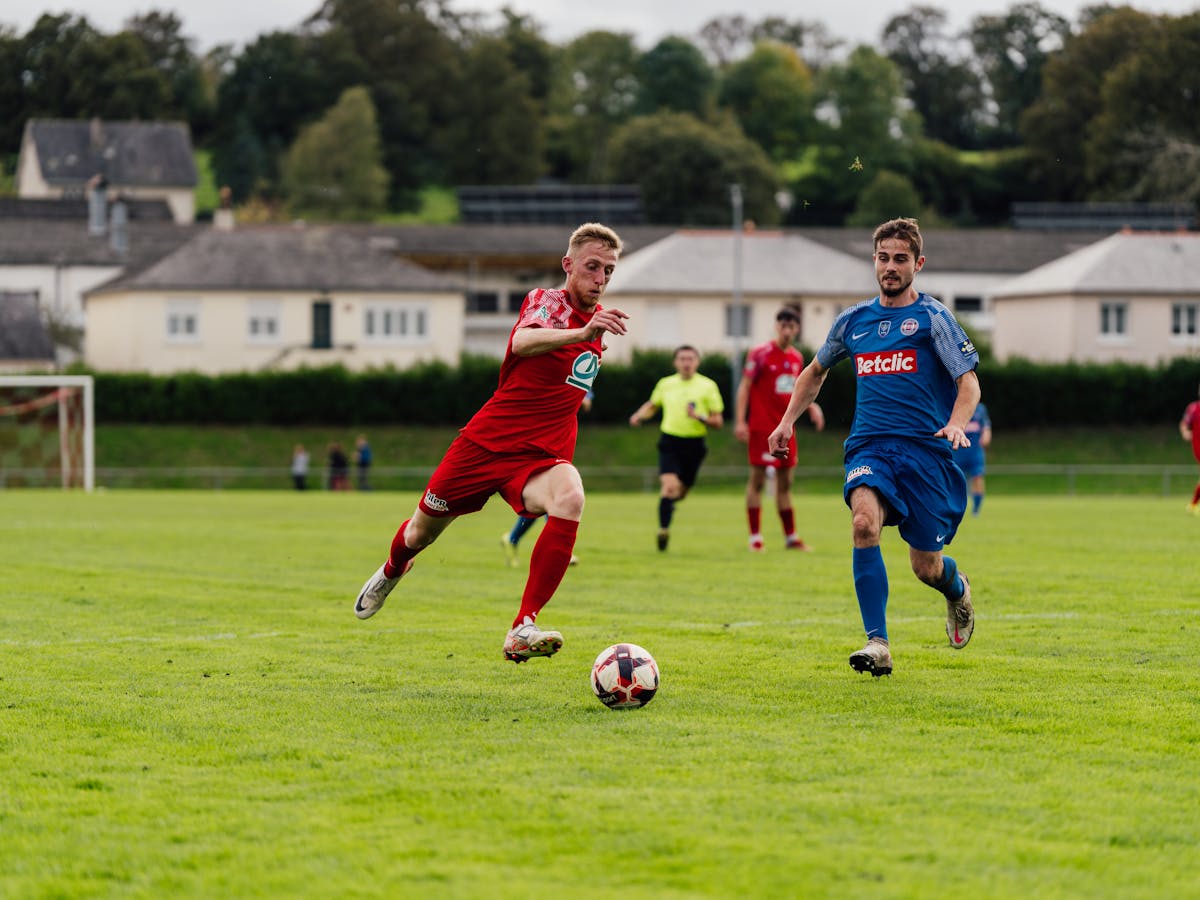 Action shot of soccer players competing on a lush green field outdoors.