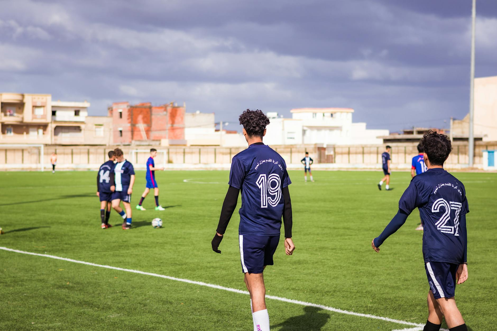 Young soccer players in blue jerseys practicing on a sunny field.