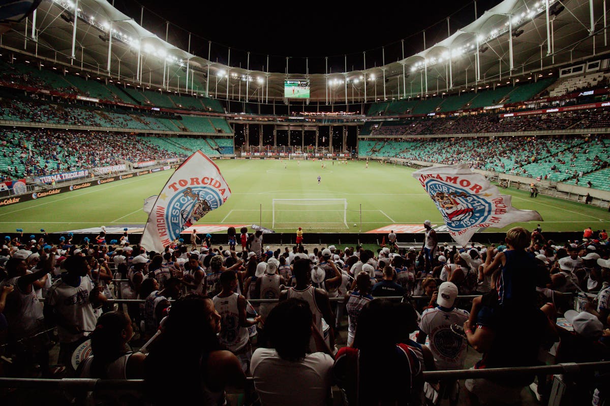 Energetic soccer fans cheer during a night match at a large stadium, creating an exciting atmosphere.