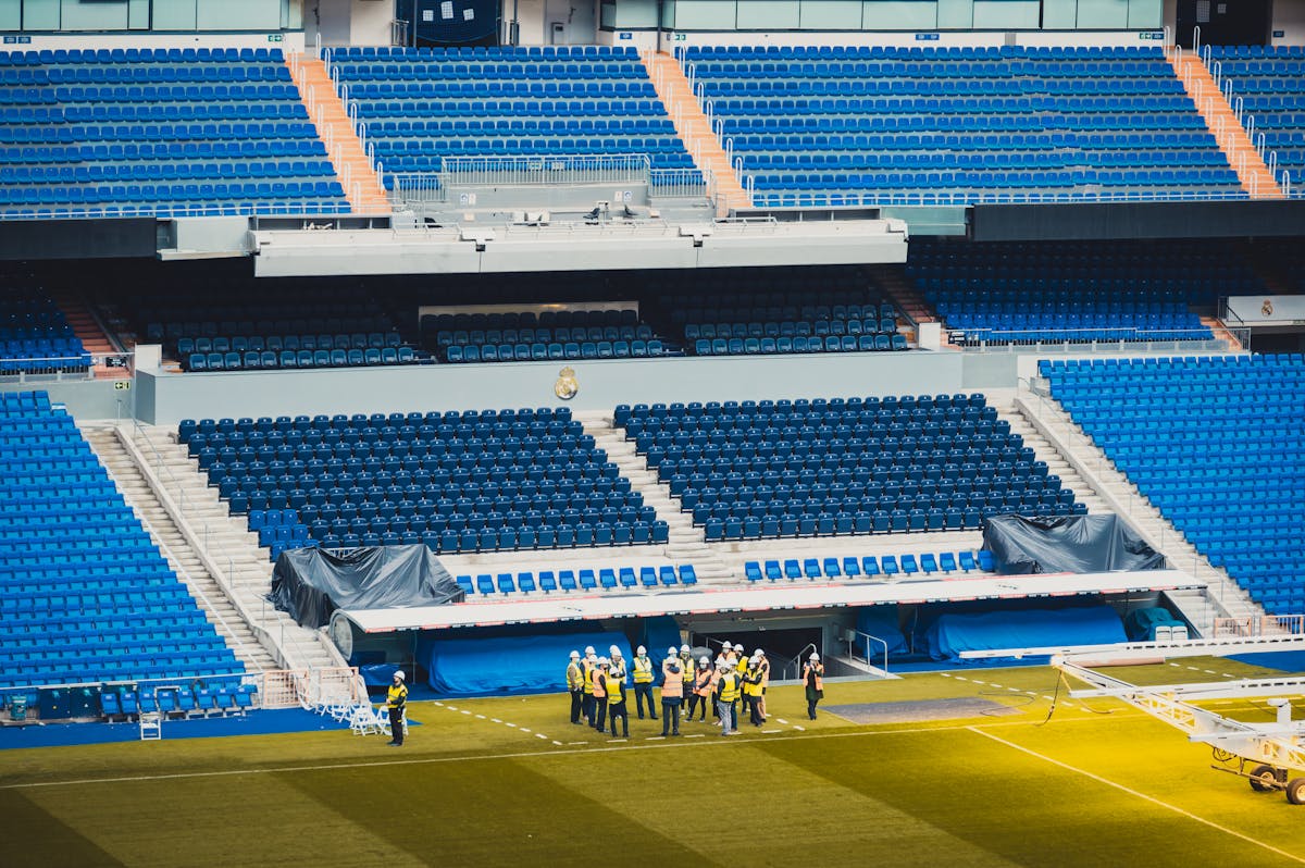 A wide-angle view of a stadium seating area in Madrid with visible workers and vibrant blue seats.